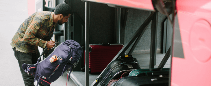 a man loads luggage into the undercarriage of a charter bus