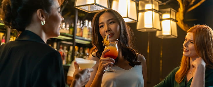 Three women sip cocktails at a bar