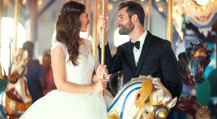 a newlywed couple take a photo on a carousel