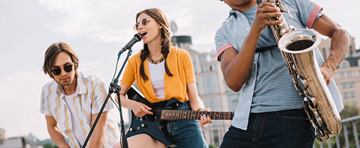 Three musicians perform on an outdoor stage