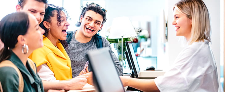 A group of young adults check in to a hotel