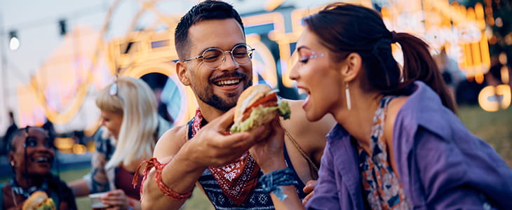 Two festival attendees eat a burger