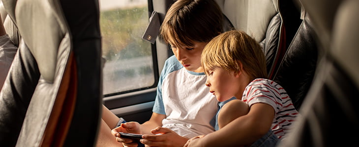 Two children play video games on a charter bus