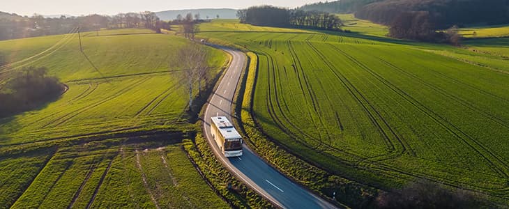 A lone charter bus on a long winding road