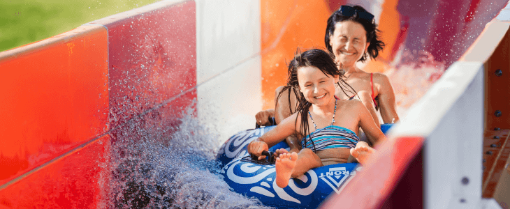 a mom and daughter slide down a waterslide