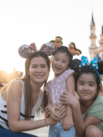 an asian family at a theme park with mouse ears